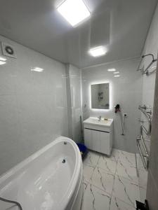 a white bathroom with a tub and a sink at Apart aero in Tashkent +9 photos