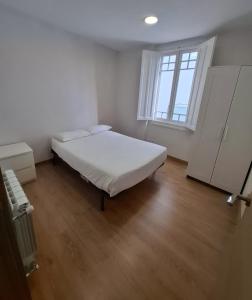 a white room with a bed and a window at La Casona Santander Centro in Santander