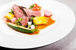 a plate of food with meat and vegetables on it at Retro Riverside Wellness Resort in Karlovy Vary