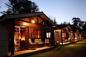 a wooden cabin with a porch with chairs and tables at Chalé Hibisco Amarelo in Juquitiba