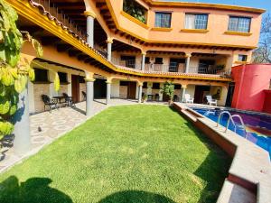 a house with a lawn in front of a swimming pool at Hotel Sta Cruz Oaxtepec in Oaxtepec