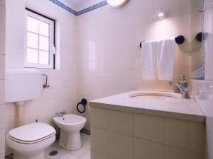 een witte badkamer met een toilet en een wastafel bij Casa Porta da Vila in Óbidos