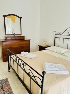 una camera da letto con un letto con un comò e uno specchio di La casa di Biu a Gela