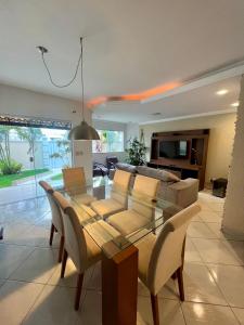 a dining room with a table and a couch at Casa com piscina, churrasqueira e ar condicionado em condomínio in Cabo Frio