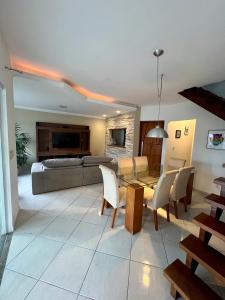 a living room with a couch and a table and chairs at Casa com piscina, churrasqueira e ar condicionado em condomínio in Cabo Frio