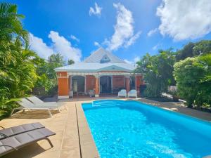 a house with a swimming pool in front of a house at Villa Douceur & Spa Piscine & Jacuzzi privés - proche plage in Saint-François