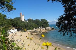 a sandy beach with a lighthouse in the background at Maison pecheur dans le banzeau in Noirmoutier-en-l'lle