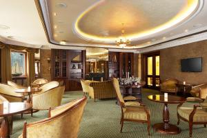 a hotel lobby with tables and chairs and a television at Retro Riverside Wellness Resort in Karlovy Vary
