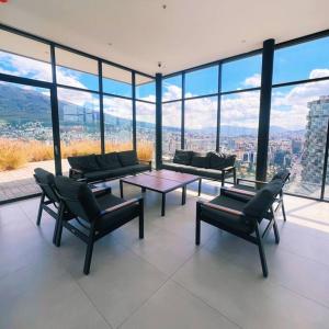 a living room with a table and chairs and glass windows at Exótico Departamento En La Carolina Edificio QORNER in Quito