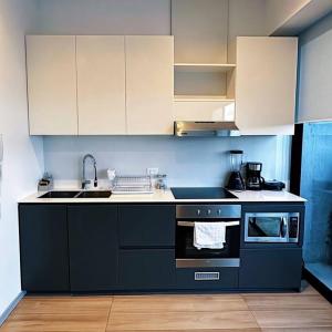 a kitchen with black and white appliances and white cabinets at Exótico Departamento En La Carolina Edificio QORNER in Quito