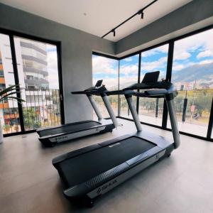 a gym with three treadmills in a room with windows at Exótico Departamento En La Carolina Edificio QORNER in Quito