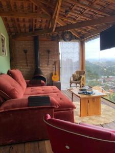 a living room with a red couch and a guitar at Charmosa Cabana Passarim, Gonçalves, Costas in Paraisópolis