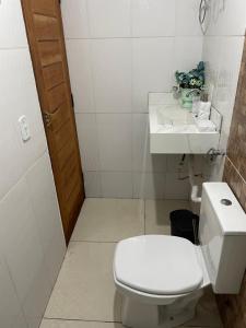 a white bathroom with a toilet and a sink at KitNet em Caraíva-Nova Caraíva in Caraíva