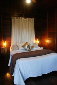 a bedroom with a large bed with white sheets and pillows at Chalé Heliconia in Juquitiba +89 photos