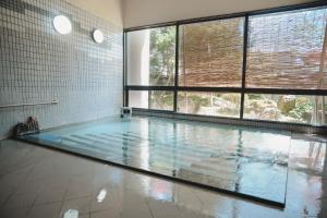 a swimming pool in a room with a large window at onogawaonsen azumasou in Yonezawa
