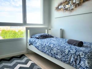 Un dormitorio con una cama con edredón azul y dos ventanas. en Le Senghor, en Courcouronnes