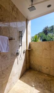 a bathroom with a shower with a glass wall at Apartment Nine at the Bayshore Resort Candidasa in Candidasa