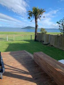 a wooden bench sitting on a patio with a palm tree at Beautiful Lakefront Location in Rotorua +9 photos