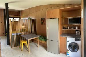 a small kitchen with a table and a refrigerator at Studio Shed in The Paddocks in Oakura