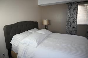 un letto con lenzuola e cuscini bianchi in una camera da letto di Elgin Suite a Niagara Falls