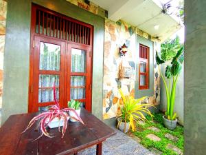 a house with a wooden table and a red door at Bosilu Villa in Weligama