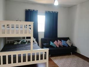 a bedroom with a crib and a couch and blue curtains at Pé na areia in Ilha Comprida