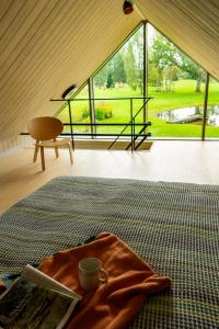 a room with a large window and a table with a coffee cup at Māja Klusumā in Jaunķempji