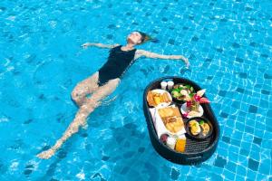 a woman in a swimming pool with a bowl of food at The Marina Phuket Hotel in Patong Beach