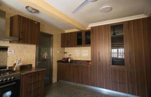a kitchen with wooden cabinets and a stove at Casa Consuelo Guest House in Sekondi-Takoradi