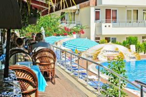 um grupo de pessoas sentadas em cadeiras perto de uma piscina em Irem Garden Hotel & Apartments em Side