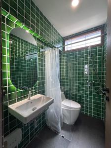 a green tiled bathroom with a sink and a toilet at Brown Brick Thonglor - Blue Blueberry Room in Klong Toi +12 photos