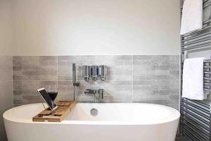 baño con bañera blanca y azulejos en Nyth Glan y Môr, Modern Luxury Lodge with Hot Tub, en Pembrokeshire 15 fotos más