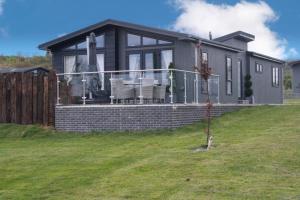 una casa en una colina con una valla en Nyth Glan y Môr, Modern Luxury Lodge with Hot Tub, en Pembrokeshire