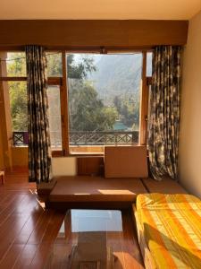 a room with a bed and a large window at aashini homestay in Vashisht