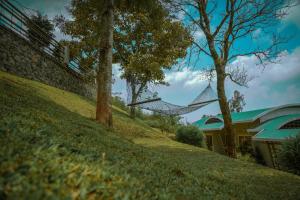 a grassy hill with a house and a building at Windale Resorts in Pooppara