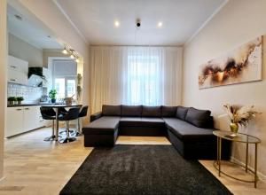 uma sala de estar com um sofá preto e uma cozinha em The Oasis - Heart of Riga em Riga