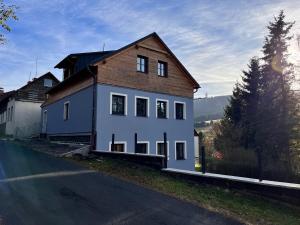 una casa blanca con techo marrón en una calle en Apartmány Quattro, en Loucná pod Klínovcem