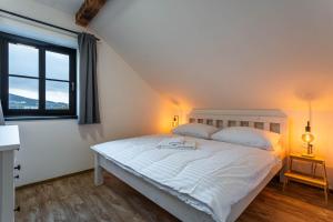 Un dormitorio con una gran cama blanca con ventana. en Apartmány Quattro, en Loucná pod Klínovcem