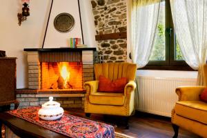 een woonkamer met een open haard en een stoel en een tafel bij Villa Natsi in Aspróyia