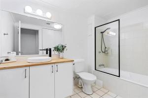 a white bathroom with a sink and a toilet at Stylish 2-BR Apartment in Gold Coast +9 photos