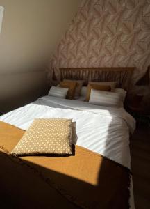a large bed with white sheets and brown pillows at Chambre et salle de bain privée in Santes