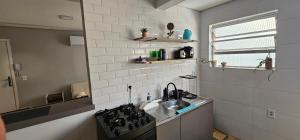 a small kitchen with a sink and a stove at Vila Caiçara Apê a 40m da Praia in Solemar