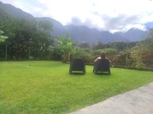 a woman sitting in a chair in the grass at CASA GIRASSOL " uma Janela para o Nascer do Sol " in São Vicente