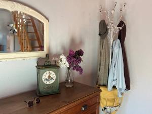 a table with a clock and a vase of flowers at Maison Au bois du Haut Folin in Saint-Prix