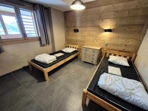 a room with two beds and a wooden wall at La Residence - Appartement La résidence MAE-9451 in Vénosc