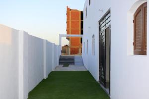 库塞尔Amoaj hotel فندق امواج的一条白色建筑走廊,有绿色的草