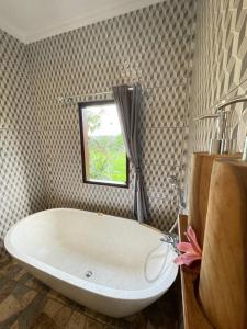 a bath tub in a bathroom with a window at Tirta Unda Sidemen in Sidemen