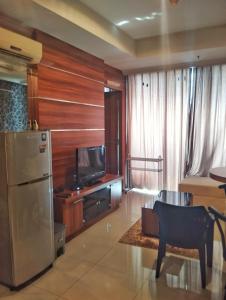 a living room with a refrigerator and a tv at Ancol Mansion Apartment Sea View by Berlin Village in Jakarta