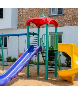 um playground com escorregador e guarda-sol em Giana’s stays with pool em Mombaça