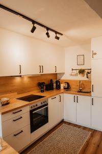 a kitchen with white cabinets and a stove top oven at JASTA Homes Mosel, zentral, Netflix, Waschmaschine, Terrasse, Privateingang, Erdgeschoss, ältester Weinort Deutschlands in Neumagen-Dhron +16 photos